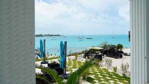 A view of a beachside area with a golf cart, umbrellas, and a clear sky. - Beautiful modern Harbour house with amazing Sunset Views ! (Black Point, Great Guana Cay)