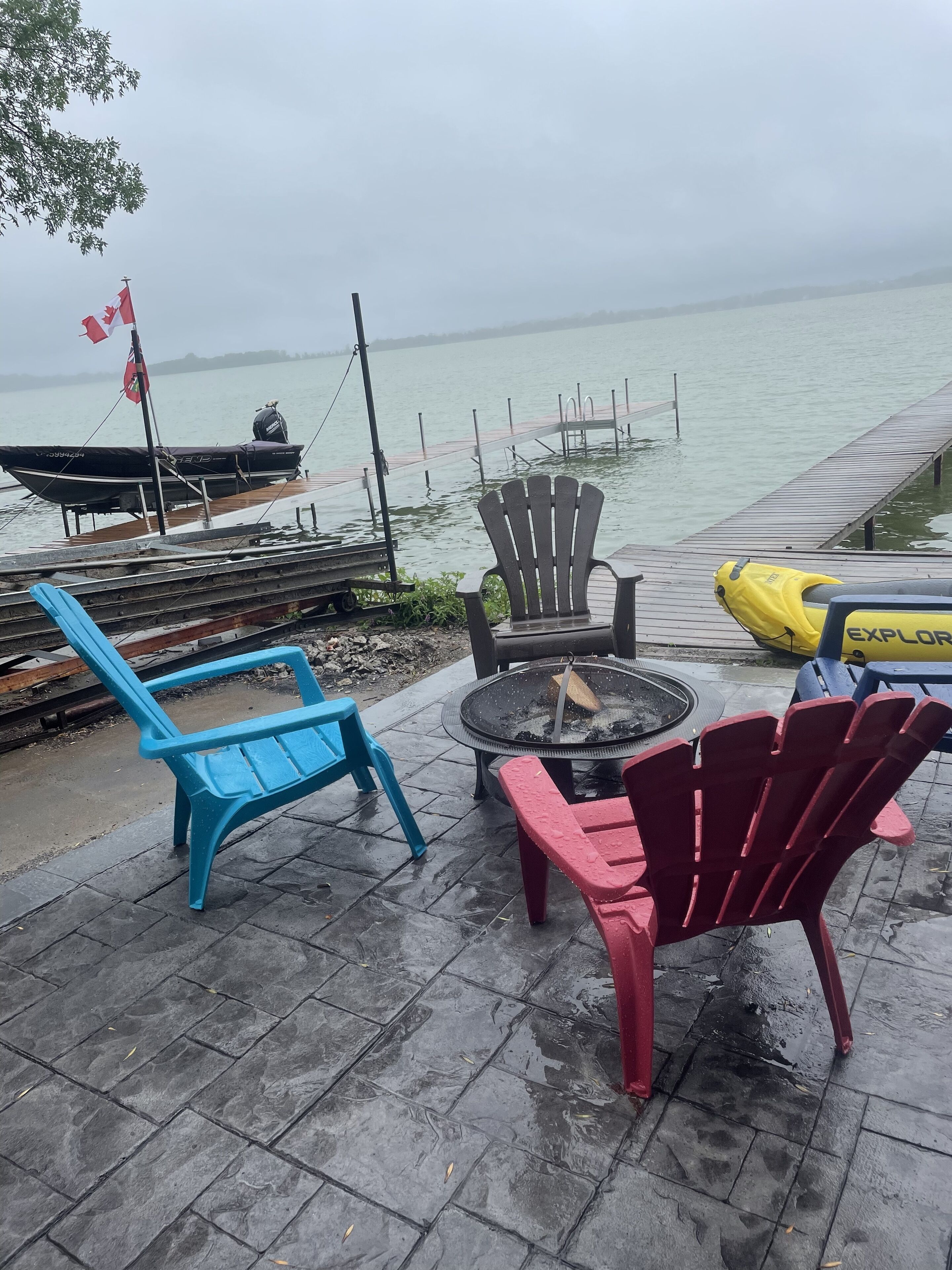 A waterfront patio with outdoor seating, a dock, and a boat.