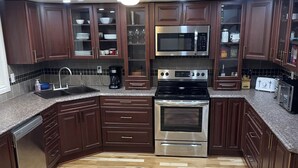 A kitchen with dark wooden cabinets, a stainless steel stove, a microwave, and a dishwasher. - Fantastic Lake Views and Gorgeous Sunsets All year round (Nestleton Station)