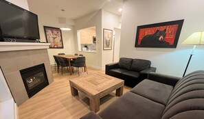 A modern living room with a fireplace, a dining area, and a kitchen.