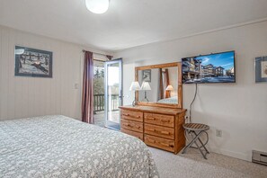 Une chambre à coucher avec un lit, une commode, un miroir et un téléviseur fixé au mur.