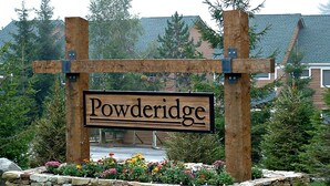 Un cartello di legno con il nome 'Powderidge' in un contesto rurale, con muri in pietra e vegetazione.