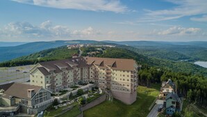 A multi-story hotel with a central courtyard, surrounded by lush greenery and a lake. - 2 Br: Soaring Eagle #411: Luxury Lodging. Great Amenities Slope Side! (Snowshoe)