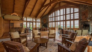 A spacious room with wooden furniture, large windows, and a stone fireplace. - 2 Br: Soaring Eagle #411: Luxury Lodging. Great Amenities Slope Side! (Snowshoe)
