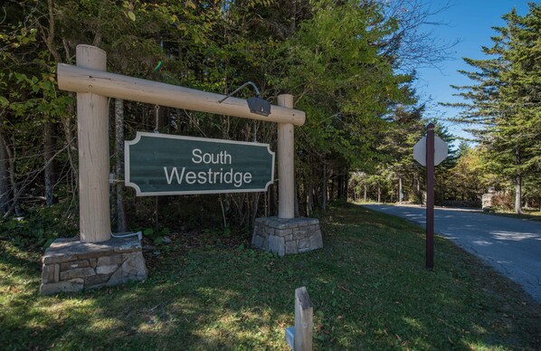A wooden signpost with "South Westridge" written on it, surrounded by greenery.