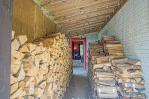 A narrow hallway with stacks of firewood on both sides, leading to a door at the end.