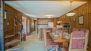 Un interior de madera con zona de comedor, escalera de madera y cocina.