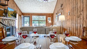 Un comedor con una mesa de madera dispuesta para seis comensales, un sofá y una araña.