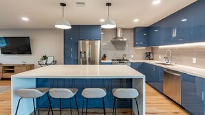 A modern kitchen with a central island, bar stools, stainless steel appliances, and blue cabinetry. - Beautiful Three Bedroom in the Center of Phoenix (Phoenix)