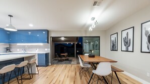 A modern kitchen with blue cabinets, a wooden dining table, and bar stools. - Beautiful Three Bedroom in the Center of Phoenix (Phoenix)