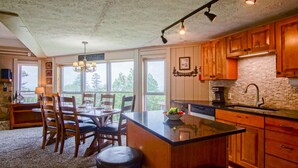 A kitchen with wooden cabinets, a large island, and a dining area with chairs and a table.
