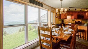 A dining area with a large table set for four, overlooking a scenic view.