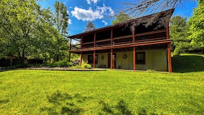 A two-story wooden house with a covered porch, surrounded by a well-maintained lawn and trees. - "Unto the Hills" Scenic and quiet cabin in Hocking Hills on 5 acres with a pond (Logan)