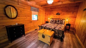 Acogedor dormitorio de cabaña de madera con cama, cómoda, aparador y ventana con vistas.
