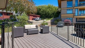 Eine Terrasse mit Gartenmöbeln, ein Gebäude mit Balkonen und ein geparktes Auto.