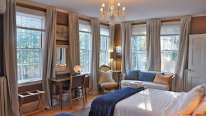 Habitación de hotel con una cama grande, un escritorio, una silla y una ventana con cortinas.