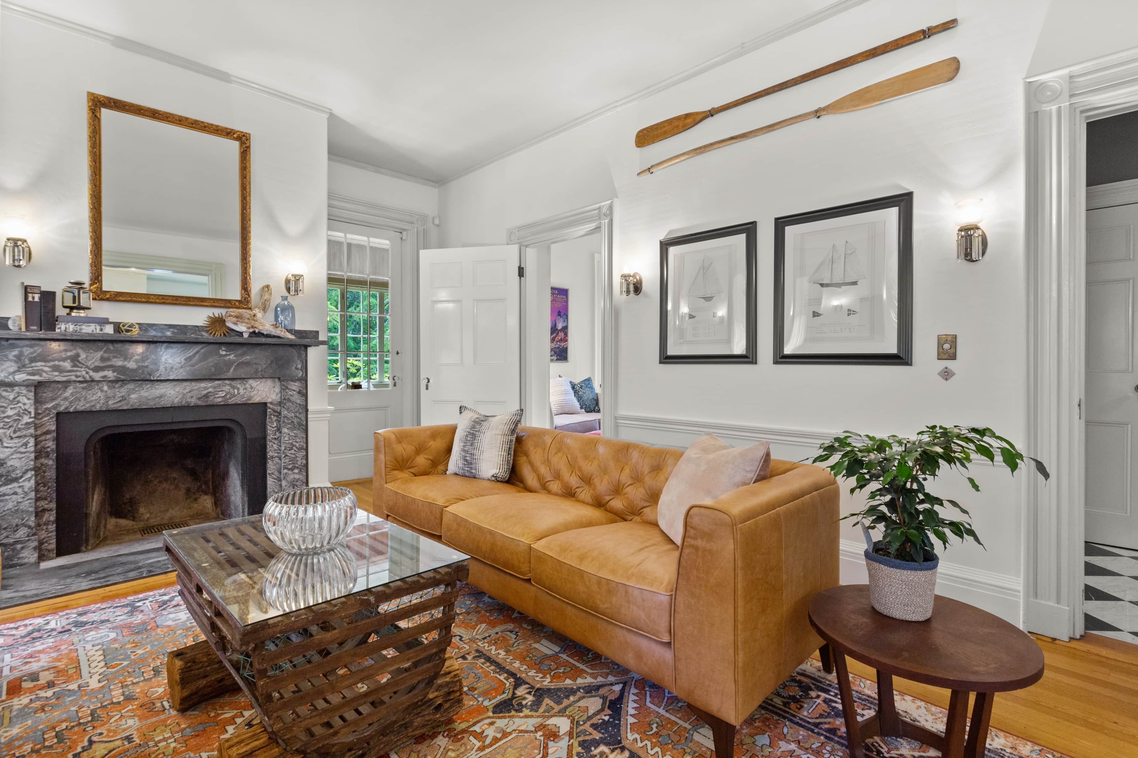 A living room with a fireplace, a leather sofa, a coffee table, and a patterned rug.