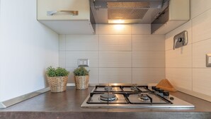 Une cuisine moderne équipée d’une cuisinière à gaz, de deux plantes en pot et d’une hotte aspirante en acier inoxydable.