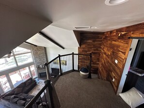 Un intérieur moderne avec un mur en bois, un escalier et un coin salon offrant une vue sur l’extérieur.