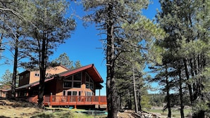 A cabin with a wooden exterior, large windows, and a deck. - Secluded Mountain Home in the Pines (Flagstaff)