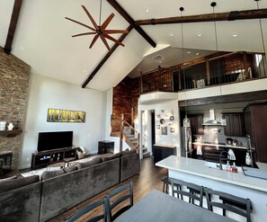 A spacious living area with a large sofa, a flat-screen TV, and a wooden ceiling. - Secluded Mountain Home in the Pines (Flagstaff)
