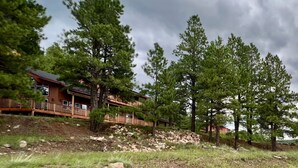 A rustic cabin with a wooden deck and a pond in the foreground. - Secluded Mountain Home in the Pines (Flagstaff)
