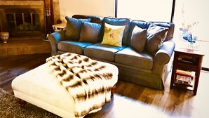 A living room with a blue sofa, a patterned ottoman, and a small table with magazines. - Roadrunner Bedroom in La Quinta Cove (La Quinta)