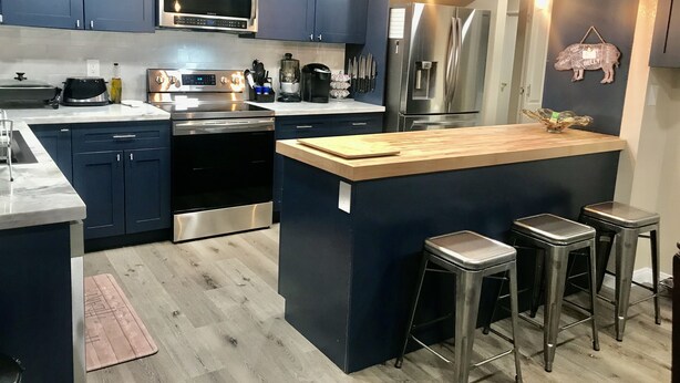 A modern kitchen with dark blue cabinets, stainless steel appliances, a central island with stools, and a wooden countertop. - Roadrunner Bedroom in La Quinta Cove (La Quinta)