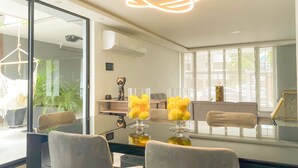 Un'area pranzo moderna con tavolo in vetro, sedie grigie e una lampada a sospensione originale.