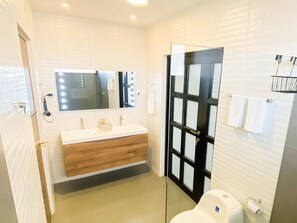 Features a spacious bathroom with a large mirror, vanity, and towel rack.