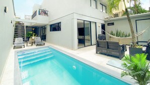 Una casa moderna con piscina, area salotto esterna e un'amaca.