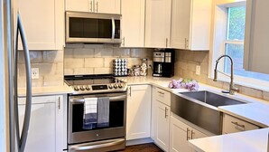 Une cuisine moderne avec des meubles blancs, des appareils électroménagers en acier inoxydable et un plancher en bois.