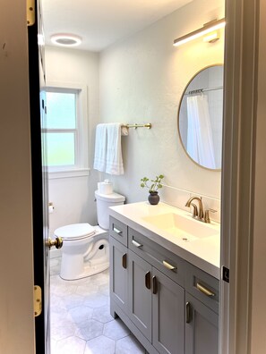Une salle de bain avec des toilettes, un lavabo, un miroir et une fenêtre.