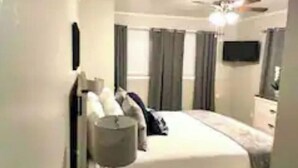 A hotel room with a bed, a bedside table, a lamp, and a ceiling fan. - Dudley's Southern Charm (Bossier City)