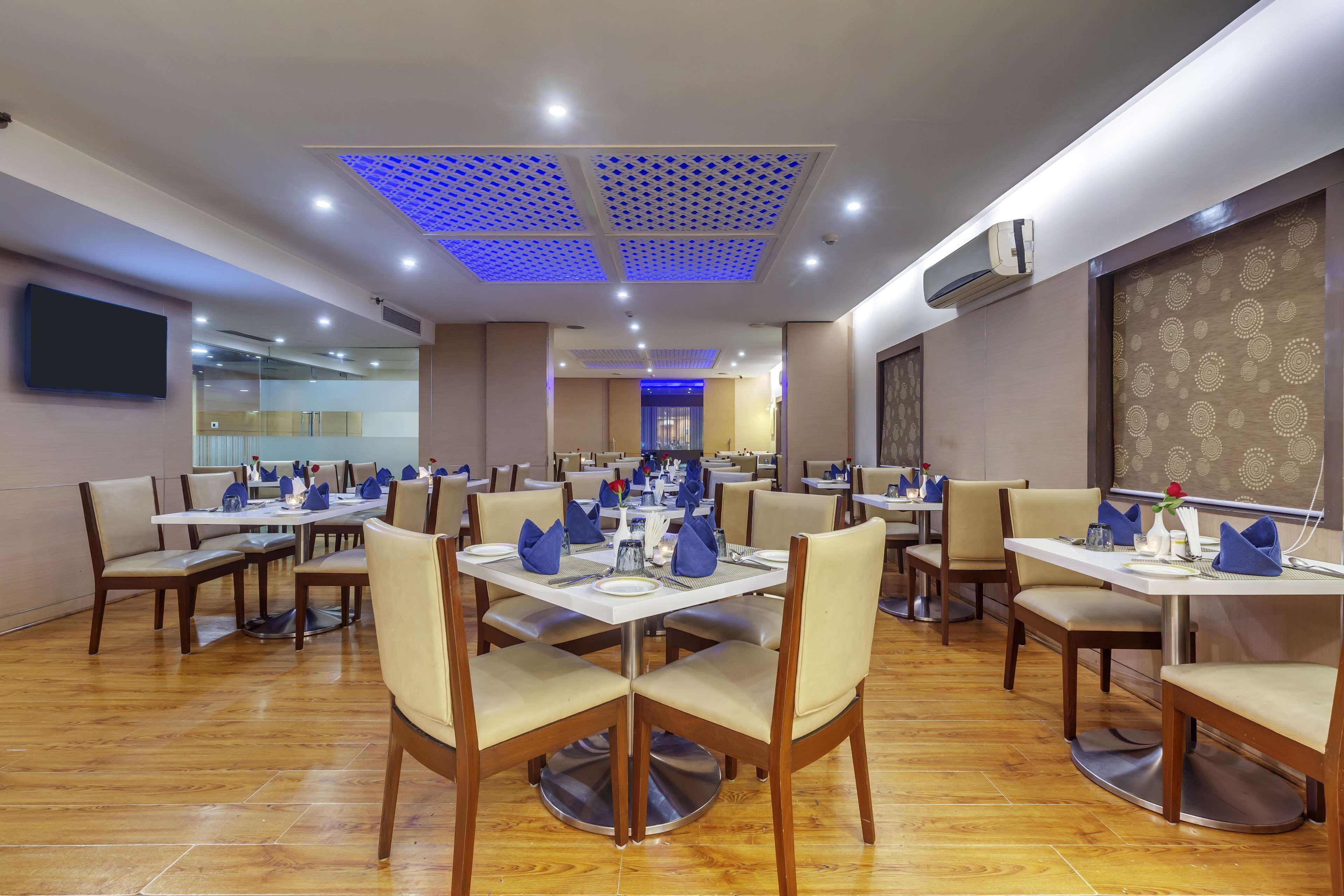 A restaurant with multiple tables and chairs, ceiling lights, and an air conditioning unit.