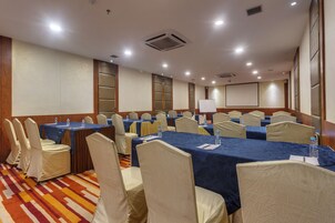 Una sala de conferencias con mesas y sillas, equipada con botellas de agua y tarjetas de identificación.