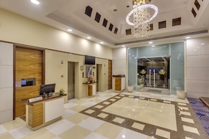 A hotel reception area with a reception desk, a chandelier, and a patterned floor.