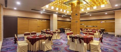 A conference room with round tables, chairs, and a patterned carpet.