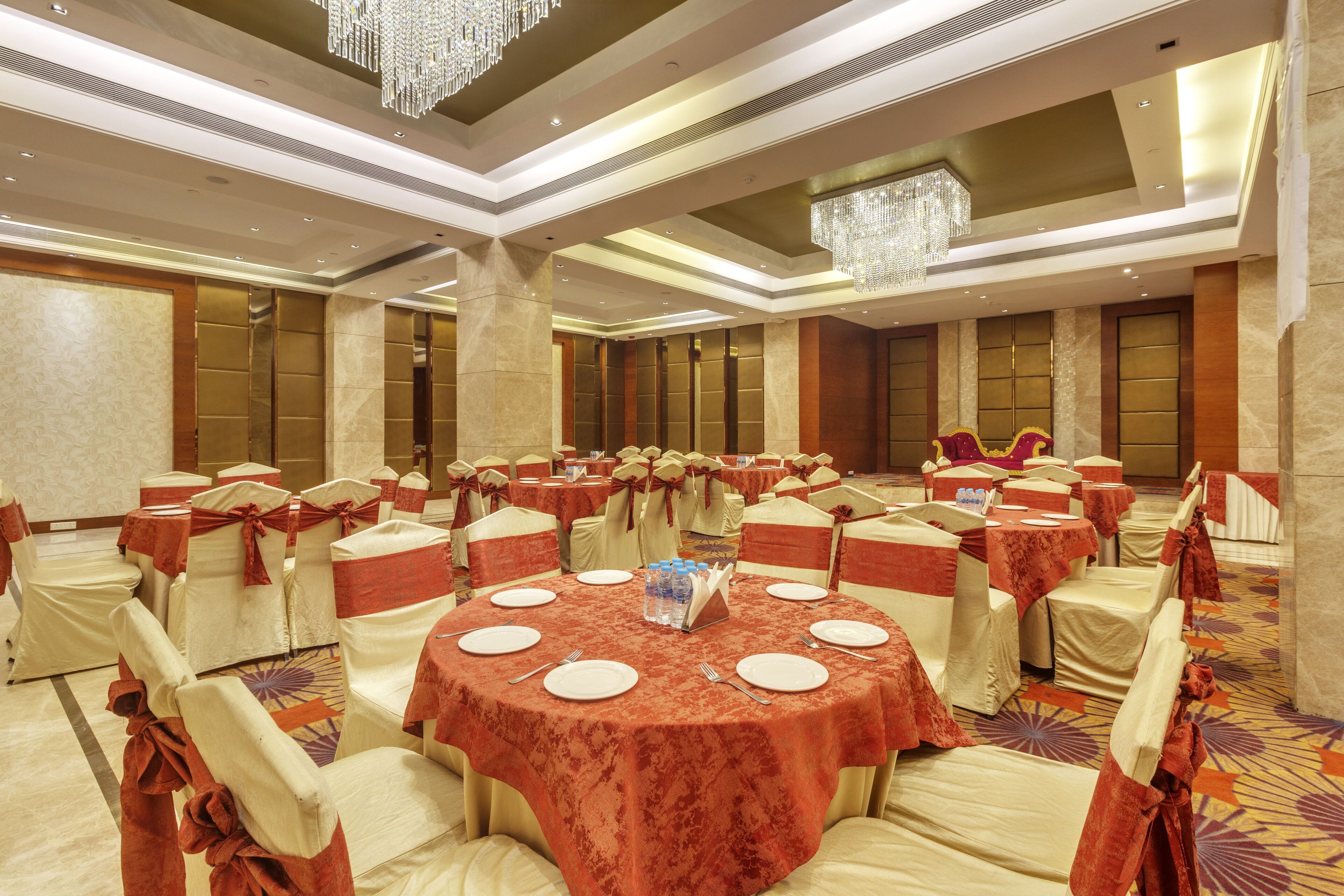 Un salón de banquetes con mesas redondas, sillas y una lámpara de araña.