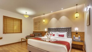 A hotel room with a large bed, a wooden headboard, a bedside table with a water bottle, and a wall-mounted lamp. - Golden Tulip New Delhi - Hari Nagar (New Delhi)