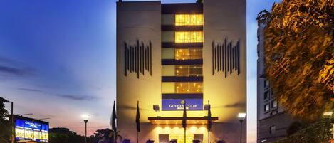 A hotel with a prominent sign, multiple floors, and a parking lot with cars.