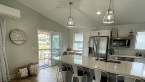 Una cocina moderna con una isla central, taburetes de bar y un comedor.