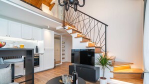 Un espacio habitable moderno con una escalera, cocina, comedor y televisor.