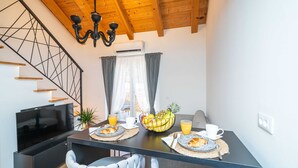 Una cocina moderna con televisor integrado, una mesa de comedor con alimentos para el desayuno y una escalera de diseño único.