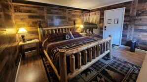 Ein rustikales Schlafzimmer mit einem hölzernen Bett, einer Wanduhr, einem Bären-Motiv und einer Tür.