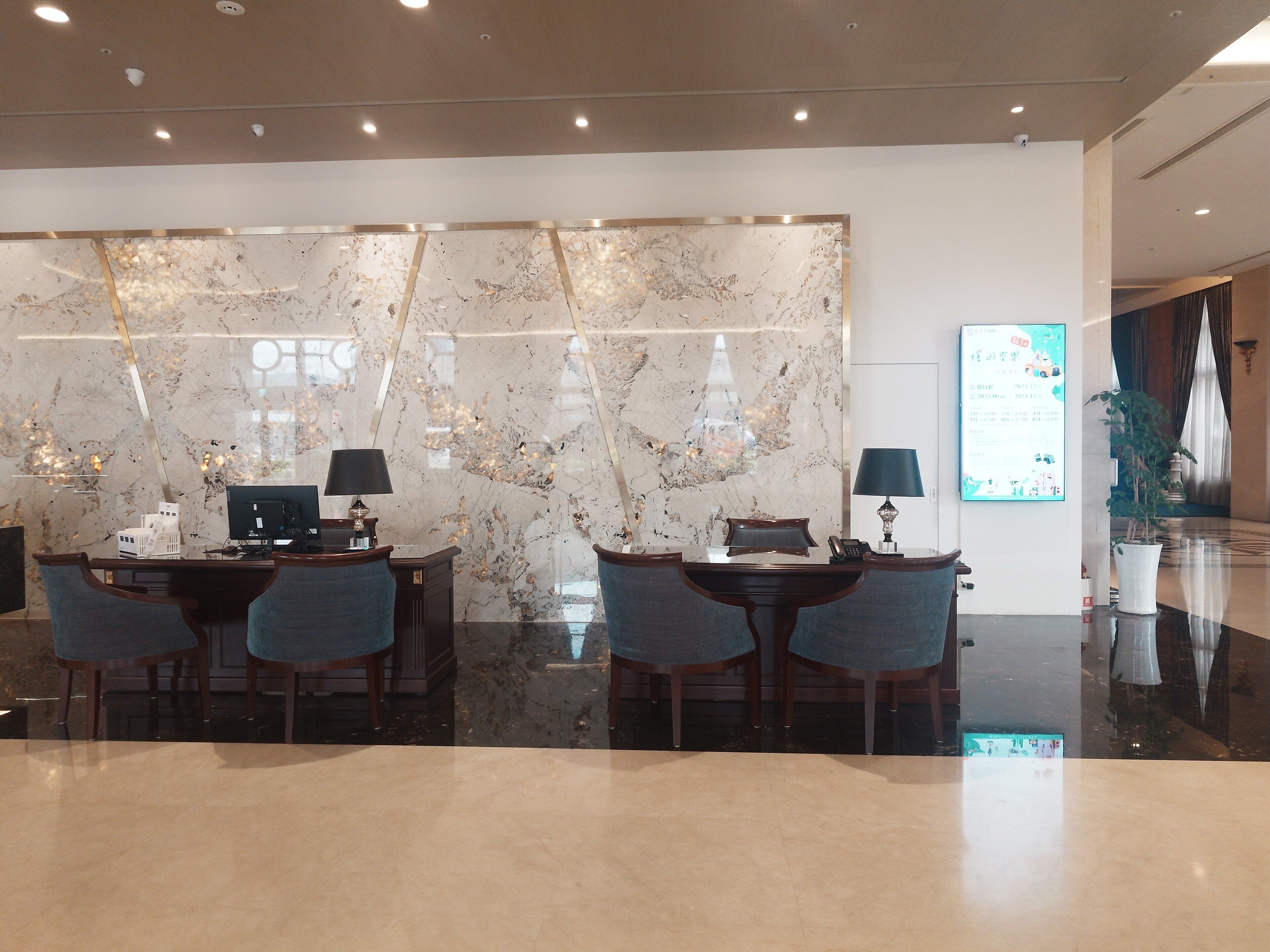 Hall d'hotel moderna con pareti in marmo, reception e area salotto.