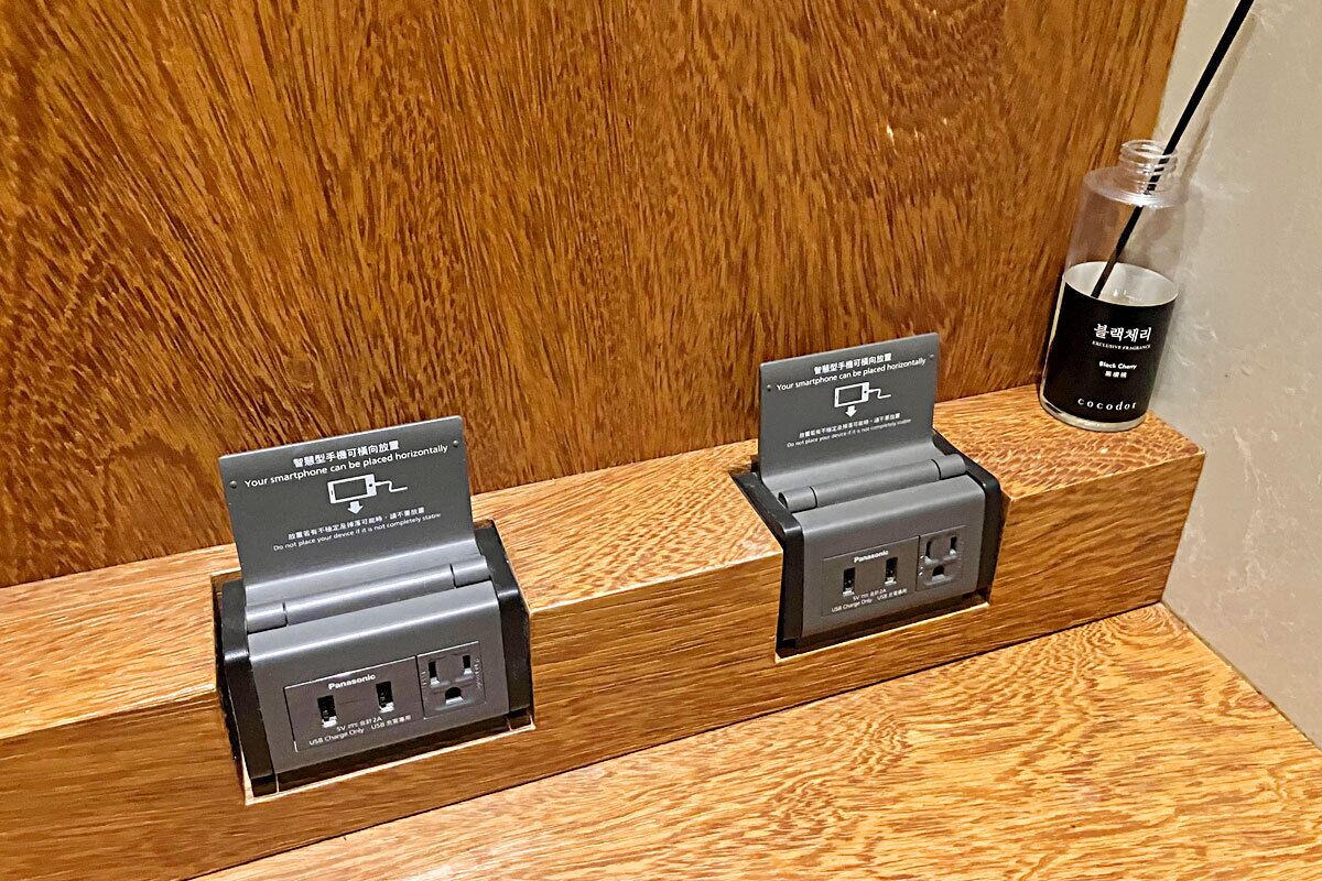 A wooden counter with two charging stations for smartphones, each with a sign indicating they are for personal use.