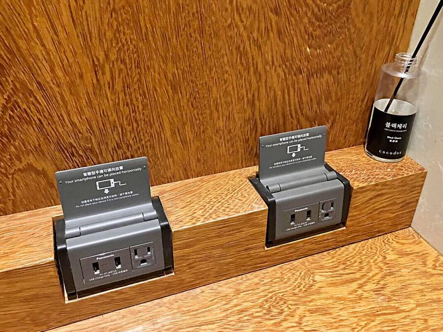 A wooden counter with two charging stations for smartphones, each with a sign indicating they are for personal use.
