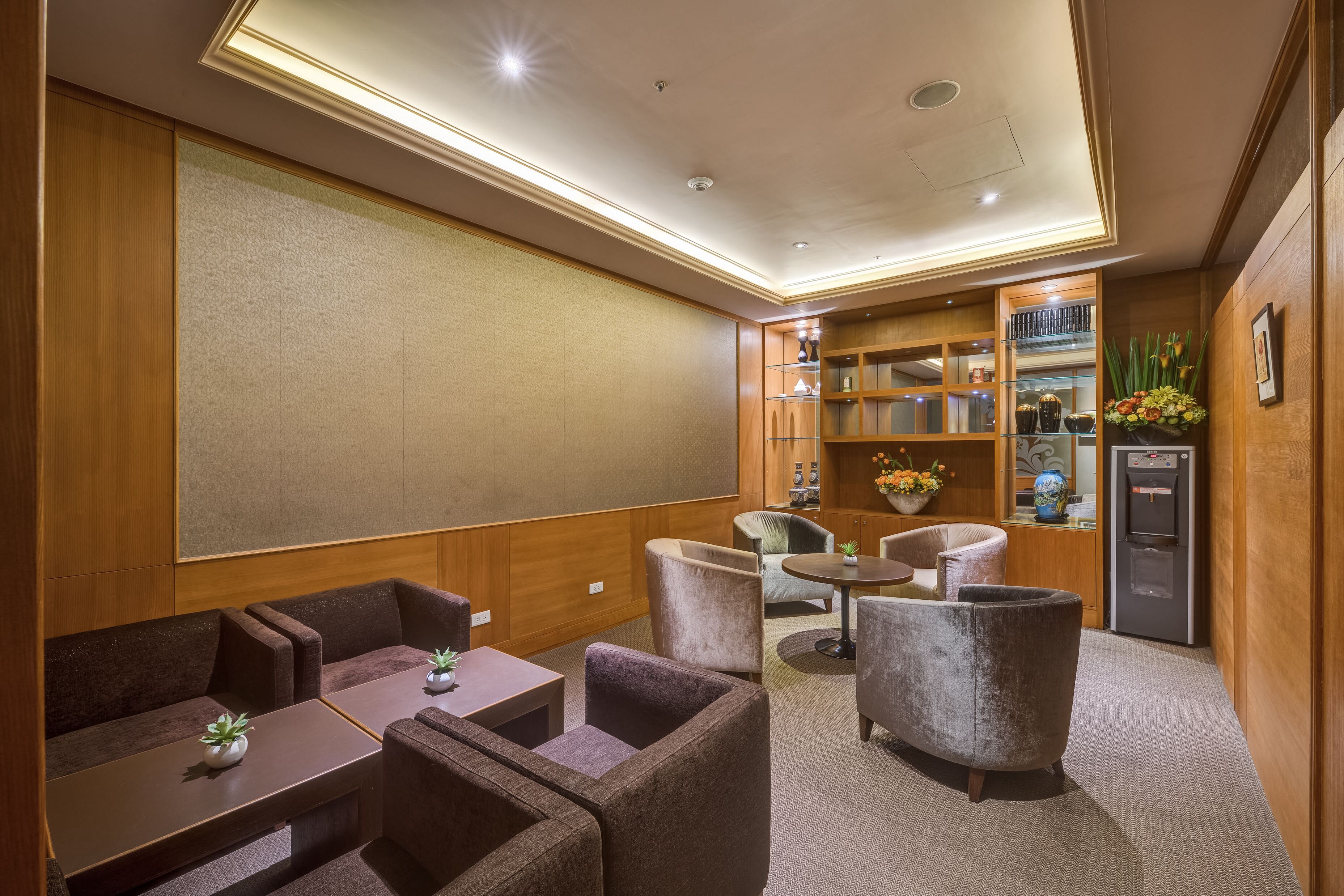 Une chambre d’hôtel dotée d’un coin salon comprenant des canapés et des fauteuils, une petite table et un réfrigérateur.
