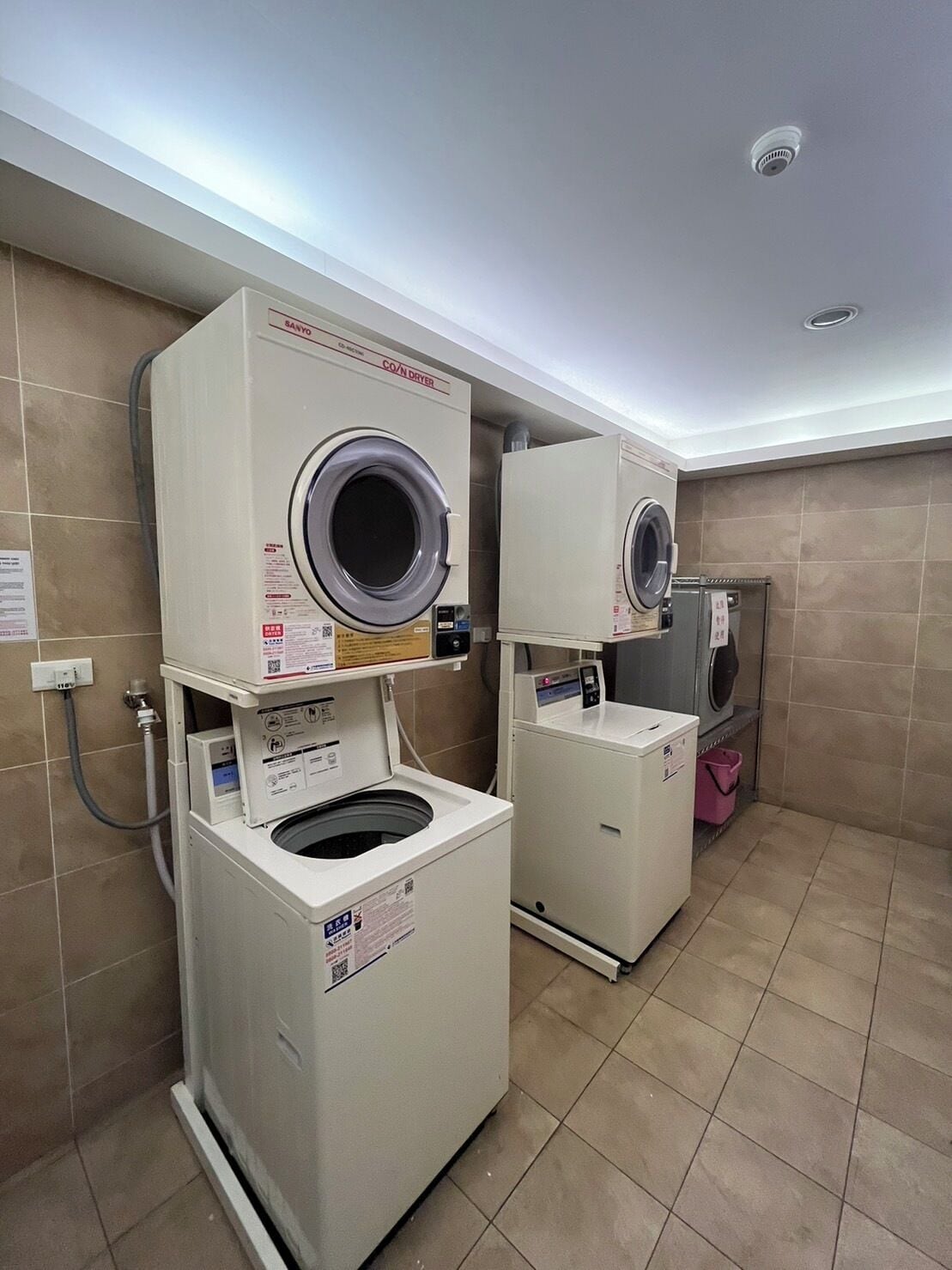 A laundry room with two stacked front-loading washing machines and a smaller one.